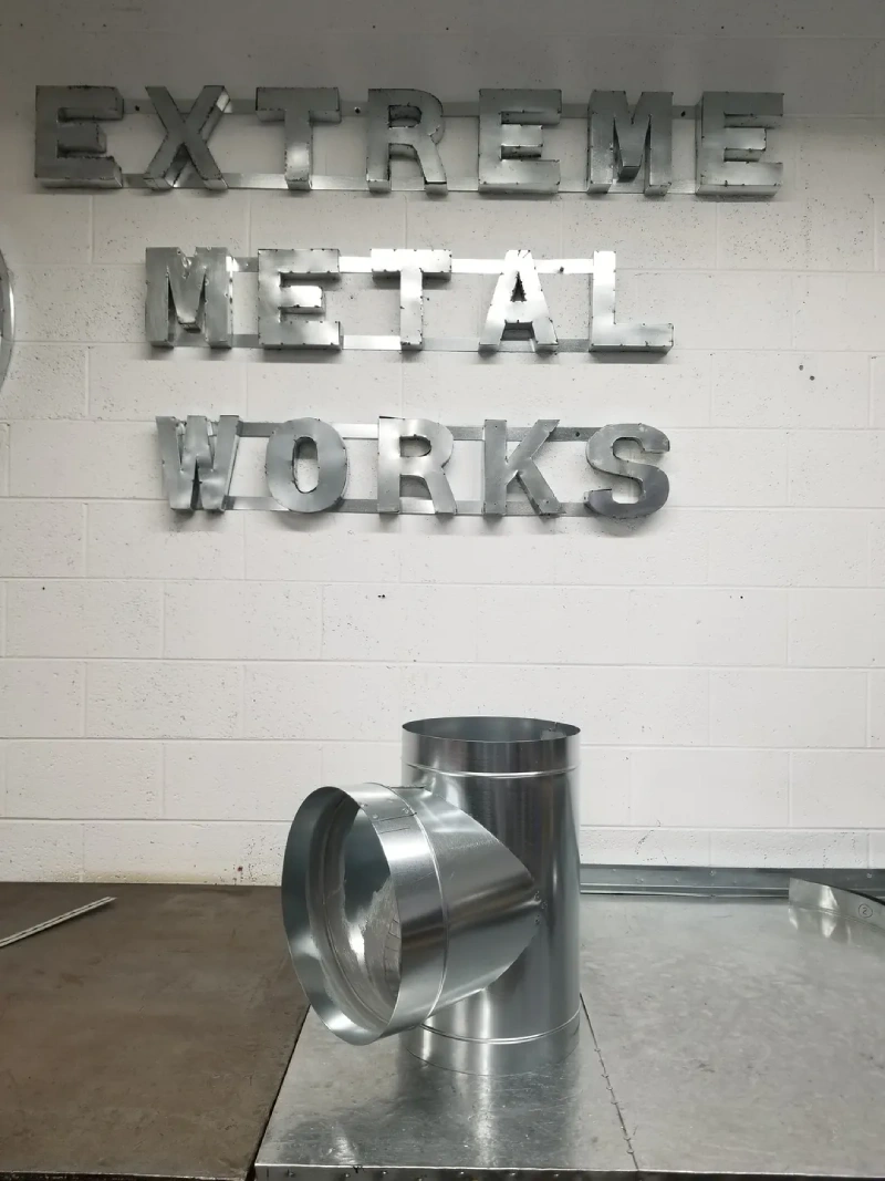 Industrial metal fittings arranged on a surface with a blurred metal works sign in the background.