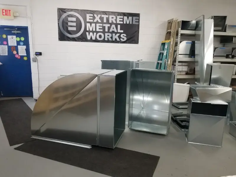 Several metal duct pieces displayed inside a workshop.