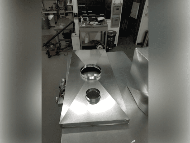 Industrial metal equipment with circular openings on top in a workshop.
