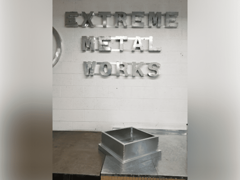 Metal balloon letters spelling 'EXTREME METAL WORKS' on a wall.